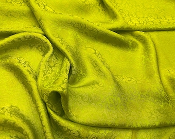 May include: A bright green fabric with a subtle floral pattern. The fabric has a smooth, silky texture.