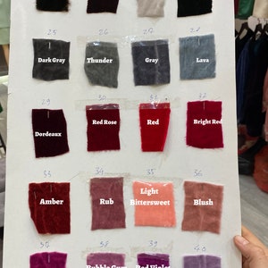 Puede incluir: Una carta de colores de muestras de tela con números y nombres para cada color. Los colores incluyen madera, jarabe, marfil, negro, gris oscuro, trueno, gris, lava, burdeos, rosa roja, rojo, rojo brillante, ámbar, frotar, ligeramente amargo, rubor, frambuesa, chicle, violeta rojo y caramelo.