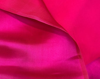 May include: Close-up of vibrant fuchsia fabric, with a smooth, silky texture. The fabric is folded, revealing layers and subtle variations in color and light. The edges are neatly finished with a delicate seam.