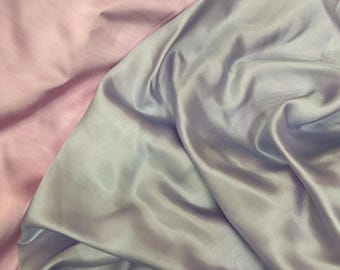 May include: A close-up of two pieces of fabric, one light pink and one light blue, both with a silky texture.