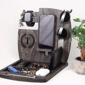 May include: A wooden organiser with a grey finish, featuring slots for a phone, watch, and sunglasses. It also has a compartment for keys, a pen, and other small items. The organiser has a personalised initial "T" engraved on the front.