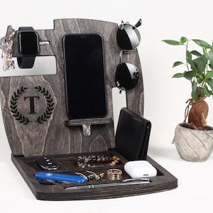 May include: Dark grey wooden desk organiser with compartments for a smartphone, watch, sunglasses, wallet, keys, and other accessories. Includes a tray for small items and a decorative initial.