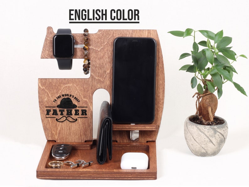 K&ouml;nnte beinhalten: Holzorganizer mit F&auml;chern f&uuml;r ein Telefon, eine Uhr und Schl&uuml;ssel. Er hat eine braune Oberfl&auml;che und die Worte "To the world's best Father" sind auf der Vorderseite eingraviert.