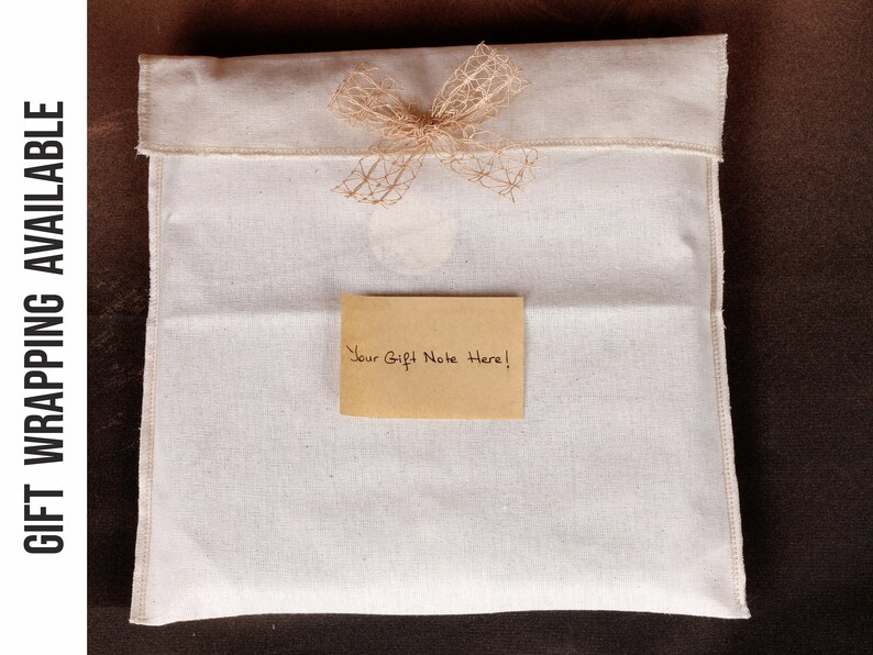 K&ouml;nnte beinhalten: Eine wei&szlig;e Baumwoll-Geschenkverpackung mit einer braunen Jute-Schleife und einem braunen Papier-Geschenkanh&auml;nger mit der Aufschrift "Your Gift Note Here!"