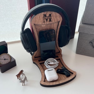 Pode incluir: Um suporte para fones de ouvido de madeira com um suporte para telefone, um pequeno compartimento de armazenamento e uma unidade USB. O suporte &eacute; personalizado com a letra "M" e o nome "Oliver".