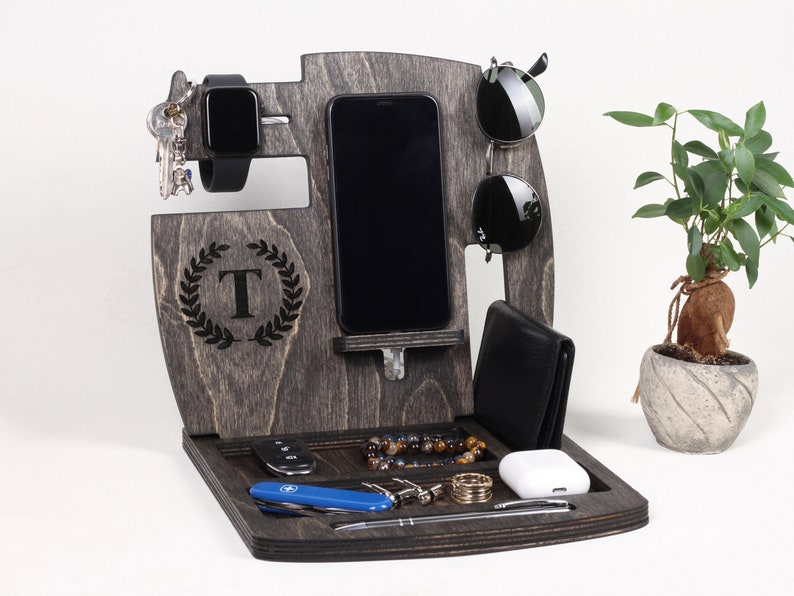 May include: Dark grey wooden desk organiser with compartments for a smartphone, watch, sunglasses, wallet, keys, and other accessories. Includes a tray for small items and a decorative initial.