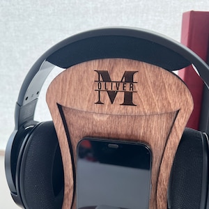 Pode incluir: Suporte de madeira para fones de ouvido com um suporte para telefone. O suporte &eacute; personalizado com a letra "M" e o nome "Oliver" gravado nele.