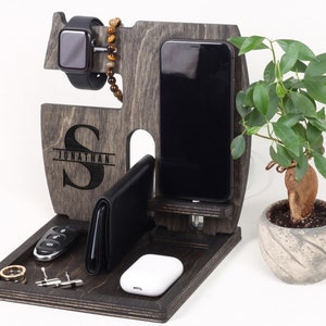 K&ouml;nnte beinhalten: Ein dunkler Holzorganizer mit einem personalisierten Initial "S" und dem Namen "Jonathan", der auf der Vorderseite eingraviert ist. Er hat F&auml;cher f&uuml;r ein Telefon, eine Uhr, eine Brieftasche und Schl&uuml;ssel. Es gibt auch ein kleines Fach f&uuml;r Ringe und Manschettenkn&ouml;pfe.