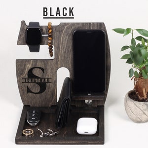 K&ouml;nnte beinhalten: Ein Holzorganizer mit schwarzer Oberfl&auml;che. Er hat F&auml;cher f&uuml;r ein Telefon, eine Uhr und eine Brieftasche. Der Organizer hat auch ein kleines Fach f&uuml;r Schl&uuml;ssel und andere Kleinigkeiten. Der Organizer ist mit dem Namen "Jonathan" und dem Initial "S" personalisiert.