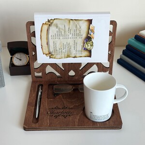 May include: A wooden desk organiser with a personalised name "Charlotte" engraved on the front. It features a pen holder, a glasses holder, a mug holder, and a book stand. The organiser is made of dark brown wood and has a decorative design.