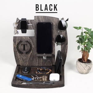 May include: Dark grey wooden desk organiser with sections for a phone, watch, keys, sunglasses, wallet, and accessories. The organiser has a tray at the bottom and a small plant in a pot. The word "BLACK" is at the top.