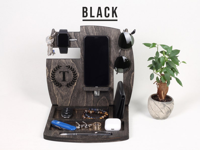 May include: Dark grey wooden desk organiser with sections for a phone, watch, keys, sunglasses, wallet, and accessories. The organiser has a tray at the bottom and a small plant in a pot. The word "BLACK" is at the top.