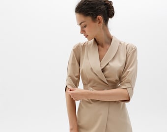 May include: A beige blazer with a long, pointed collar and a double-breasted closure. The blazer has three-quarter sleeves and a fitted silhouette.