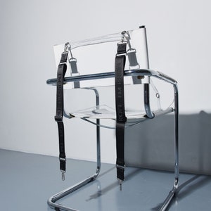 a clear chair with black straps on it