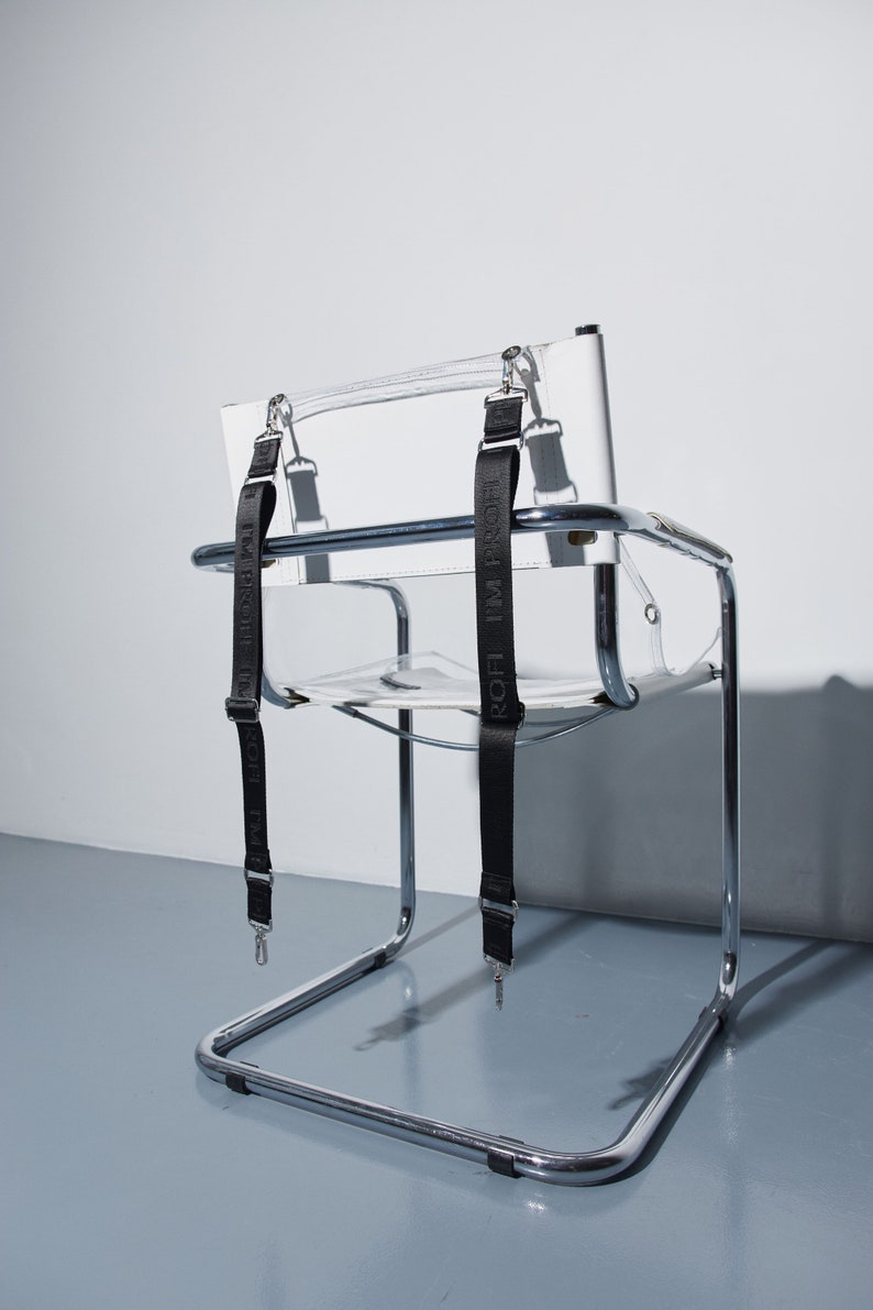 a clear chair with black straps on it
