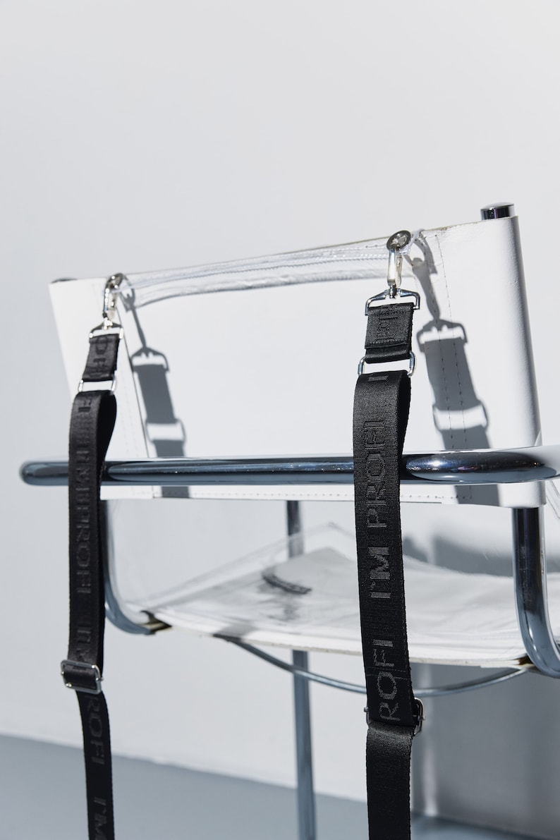 a clear chair with a black strap on it