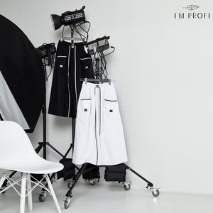 May include: Two long skirts, one black and one white, are displayed on a clothing rack. Both skirts have black trim and pockets. The skirts are on a white background with the text "I'M PROFI" in the top right corner.