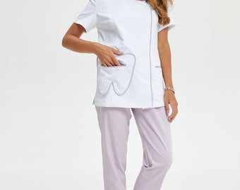 May include: White dental uniform set with a tooth-shaped pocket design. The top has short sleeves and a zipper, paired with light purple pants and lavender clogs. A professional and functional outfit.