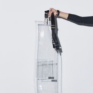 a woman is holding a clear case with a black strap