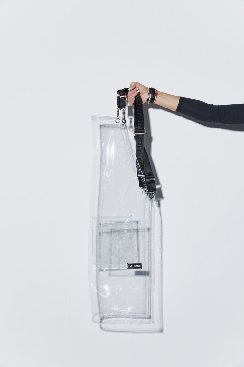 a woman is holding a clear case with a black strap