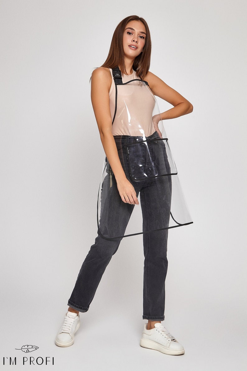 May include: A clear plastic apron with black trim and a black adjustable strap. The apron has a large pocket on the front and a smaller pocket on the side.