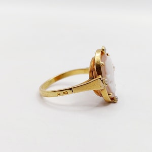 May include: A gold ring with a cameo set in the center. The cameo is a white shell with a carved portrait. The ring is set with small diamonds around the cameo.