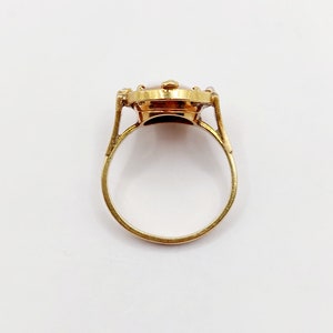 May include: A gold ring with a brown oval stone set in a bezel setting. The stone is surrounded by smaller diamonds.