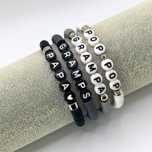 May include: Four beaded bracelets with black and white beads spelling out "Papa", "Gramps", "Grampa", and "Pop Pop".