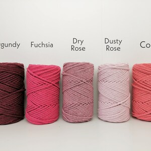 K&ouml;nnte beinhalten: F&uuml;nf Spulen Baumwollschnur in verschiedenen Rosat&ouml;nen und Rot. Die Farben sind von links nach rechts beschriftet: Burgunder, Fuchsia, Trockenrose, Staubrose und Koralle.