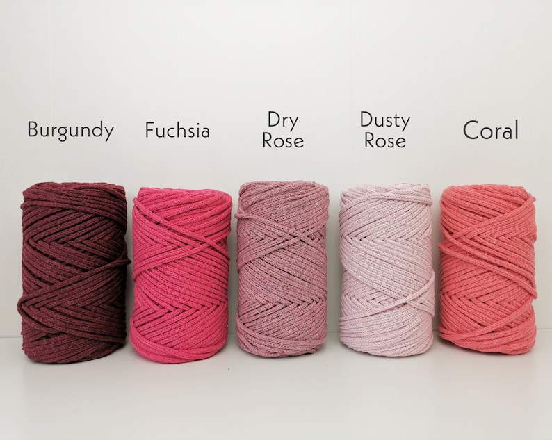 K&ouml;nnte beinhalten: F&uuml;nf Spulen Baumwollschnur in verschiedenen Rosat&ouml;nen und Rot. Die Farben sind von links nach rechts beschriftet: Burgunder, Fuchsia, Trockenrose, Staubrose und Koralle.