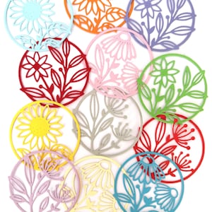 May include: A collection of twelve circular coasters featuring intricate laser-cut floral and botanical designs. The coasters are rendered in a variety of vibrant colors including red, orange, yellow, light blue, green, pink, purple, and light gray.