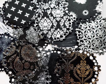 May include: A collection of black and white patterned paper doilies with scalloped edges. The designs include floral, geometric, and damask patterns. Some doilies have metallic accents, creating a contrast against the black background.