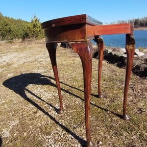 Antico tavolo da gioco di carte pieghevole in mogano, in stile georgiano, sorretto da gambe tornite che terminano con piedini a cuscinetto.