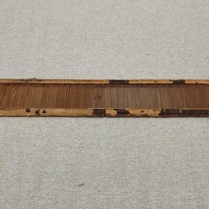 以下が含まれることがあります： 茶色の仕上げと薄い茶色の経糸を持つ木製の織機。織機は木でできており、長方形の形をしています。