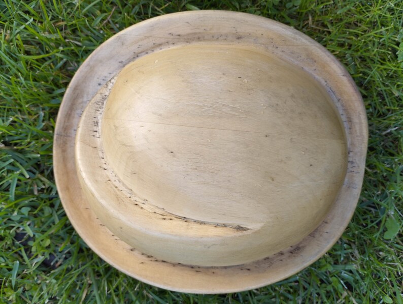 May include: A wooden bowl with a natural finish. The bowl has a deep, rounded shape and a smooth, polished surface.