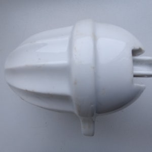 May include: White ceramic citrus juicer with a ribbed design and a spout on the side.