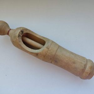 Peut inclure: Un bouchon de bouteille en bois avec un bouton rond à une extrémité et une section creusée au milieu. Le bouchon est en bois brun clair et a une bande rouge autour du bouton.