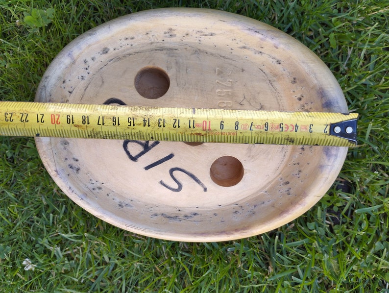 May include: A round, wooden, light brown disc with two holes and the word "SIP" written on it. The disc is 20 inches in diameter.