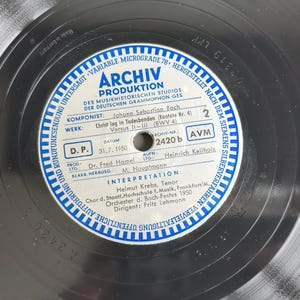 May include: A black vinyl record featuring a circular white and blue label with the text Archiv Produktion, Johann Sebastian Bach, Christ lag in Todesbanden, and details regarding the 1950 recording, including performers Helmut Krebs and Fritz Lehmann.