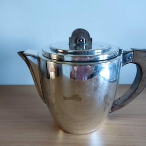 May include: A silver teapot with a wooden handle. The teapot has a round body and a lid with a decorative knob.
