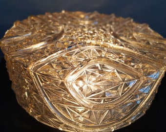 May include: A clear glass bowl with a decorative, geometric pattern. The bowl has a rounded shape and a textured surface.