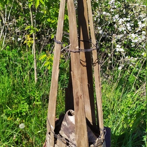 Könnte beinhalten: Eine kegelförmige Holzstruktur mit Draht umwickelt, die auf einem Holzhocker steht. Die Struktur ist aus verwittertem Holz und hat ein rustikales Aussehen.