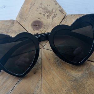 May include: Black heart-shaped sunglasses with a thick black frame.