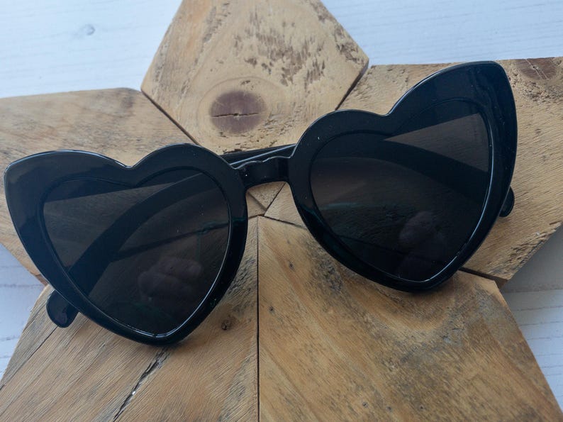 May include: Black heart-shaped sunglasses with a thick black frame.