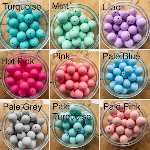 May include: A collection of nine glass bowls, each filled with round, solid-coloured silicone beads. The colours include turquoise, mint, lilac, hot pink, pink, pale blue, pale grey, pale turquoise, and pale pink, each labelled with its colour name.