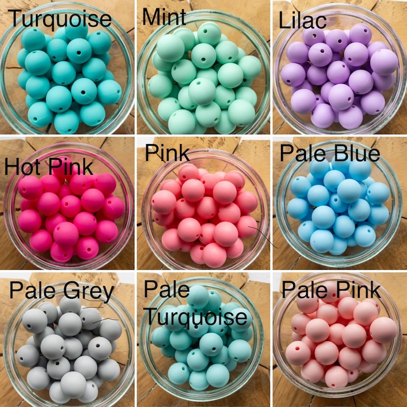 May include: A collection of nine glass bowls, each filled with round, solid-coloured silicone beads. The colours include turquoise, mint, lilac, hot pink, pink, pale blue, pale grey, pale turquoise, and pale pink, each labelled with its colour name.