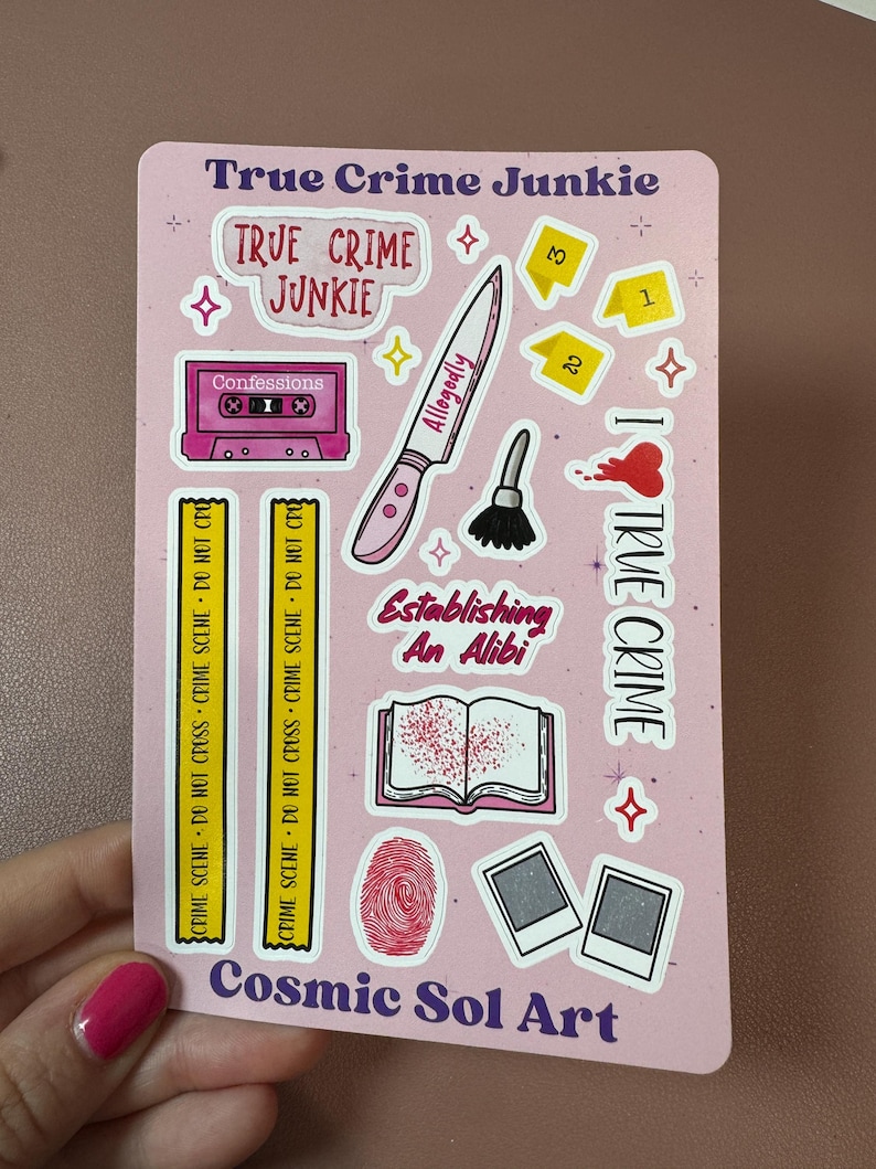 May include: A pink sticker sheet with various true crime-themed illustrations. Includes a knife, cassette tape, fingerprint, and the words "True Crime Junkie," "Allegedly," and "Establishing An Alibi." The artist's name, "Cosmic Sol Art," is also visible.