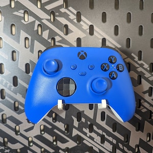 May include: A blue Xbox controller with white buttons and a black directional pad. The controller has the letters X, Y, A, and B on the buttons.