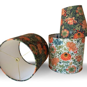 May include: Four floral lampshades in various shapes and sizes. The shades feature a botanical pattern with orange and yellow flowers, green leaves, and a dark background. One shade is cylindrical, another is conical, and the others are cylindrical.