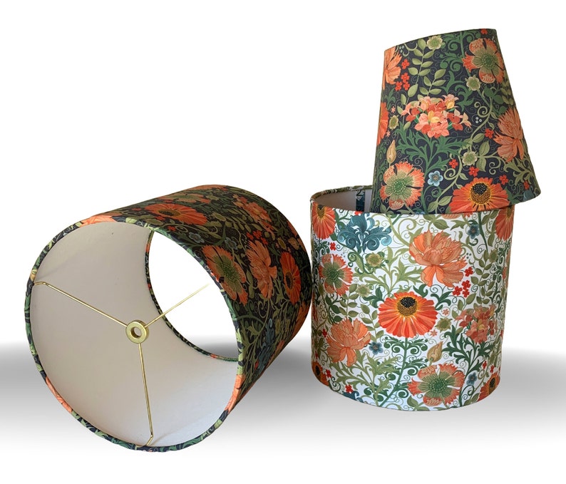 May include: Four floral lampshades in various shapes and sizes. The shades feature a botanical pattern with orange and yellow flowers, green leaves, and a dark background. One shade is cylindrical, another is conical, and the others are cylindrical.